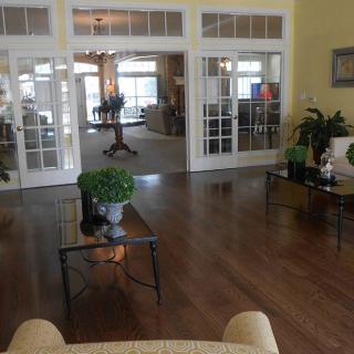 A spacious living room with wooden flooring and glass doors leading to another area of the house.