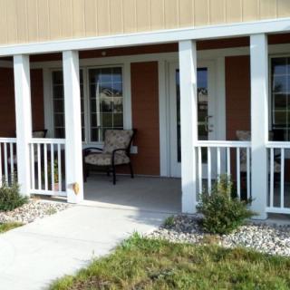 A cozy porch with seating outside a house entrance.