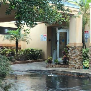 A welcoming entrance to a building surrounded by lush landscaping and palm trees.