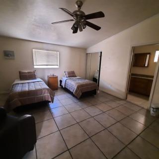 A spacious bedroom with twin beds, a ceiling fan, and an adjoining bathroom.