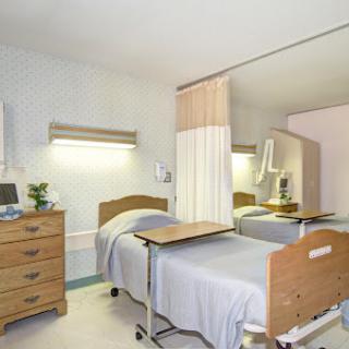 A well-lit and clean hospital patient room featuring two beds, modern medical furniture, and a soothing color palette.
