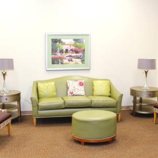 A cozy living room with a green sofa, matching chairs, and modern decor.
