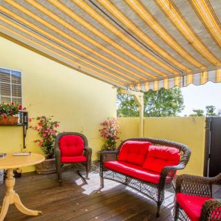 A cozy patio with red-cushioned garden furniture under a striped awning.