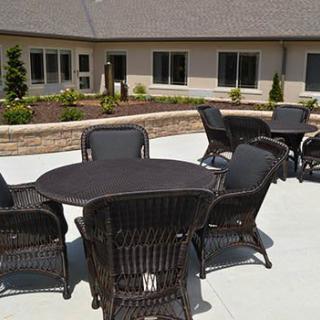 An outdoor patio area with wicker furniture and a building in the background.