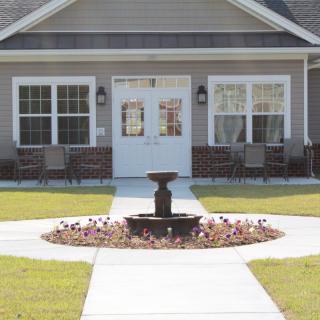 A charming house with a central fountain and well-maintained lawn.