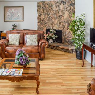 A cozy living room with a leather sofa, fireplace, and hardwood floors.