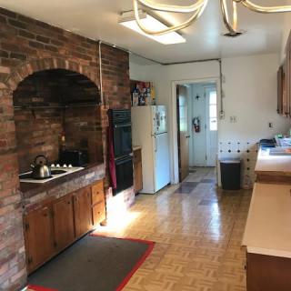 A cozy kitchen with a brick wall, featuring a stove and wooden cabinets.