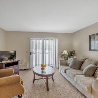 A cozy living room with a sofa, armchair, coffee table, and television.
