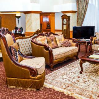 A traditionally decorated living room featuring elegant sofas, armchairs, and a grandfather clock.