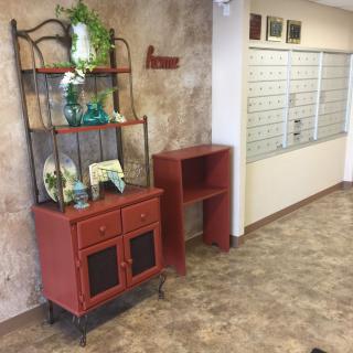 A decorated office corner with a red shelf and potted plant.