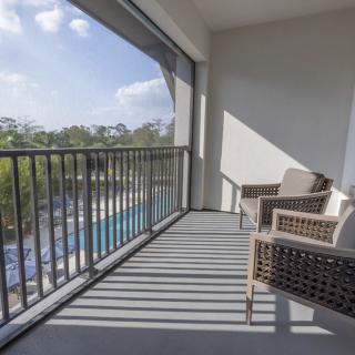 A relaxing balcony with outdoor seating overlooking a pool and nature.