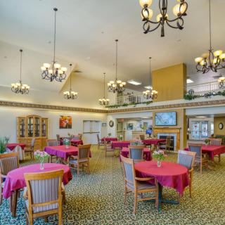 A spacious dining area with elegant chandeliers and pink tablecloths.