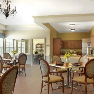 A bright and inviting dining room with elegant chairs and tables, adjacent to a kitchen area.