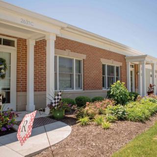 A charming brick residential house with well-maintained landscaping and a front pathway.