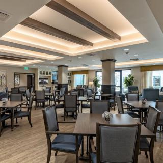 A modern and spacious dining room with neatly arranged tables and chairs, featuring warm lighting and a stylish interior design.