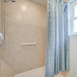 A bathroom shower area with a blue patterned curtain and a grab bar.