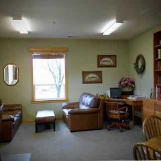 A cozy office space with a desk, chairs, and a couch.