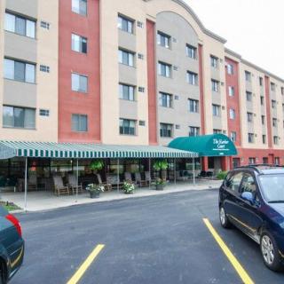 An exterior view of a hotel with a parking lot and cars in front.