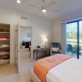 A modern bedroom with a cozy bed, stylish decor, and large windows leading to a balcony.