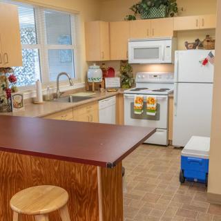A cozy kitchen with wooden cabinets, modern appliances, and a central countertop with a stool.
