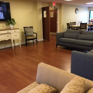 A cozy living room area with sofas, chairs, a television, and hardwood flooring.