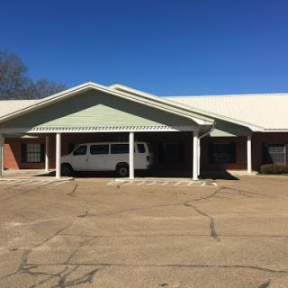 A clear view of a residential building with a white van parked in front under a blue sky.