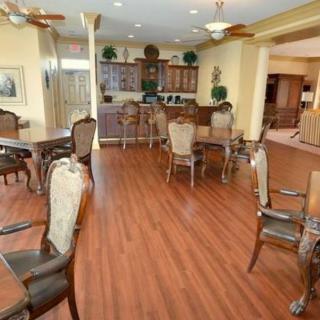 A well-lit dining room with wooden floors, tables, and chairs arranged in a cozy setting.