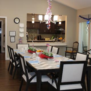 A beautifully arranged dining room with a modern touch, featuring a long table set for a gathering.