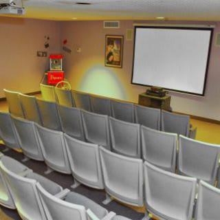 An empty small theater with a projection screen and rows of seats.