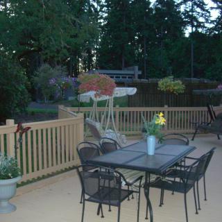 A peaceful backyard patio with a table, chairs, and various plants.