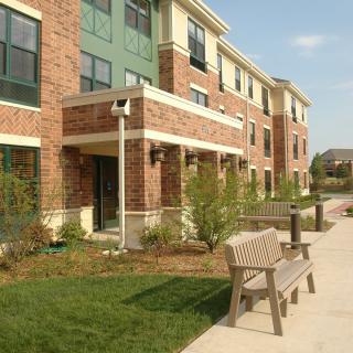 A residential apartment building with a bench and landscaped pathway.