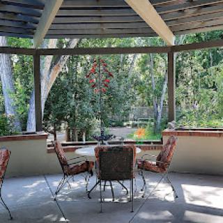 A serene outdoor seating area in a gazebo surrounded by lush greenery.