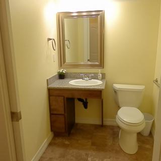 A simple bathroom with a vanity, mirror, and toilet.