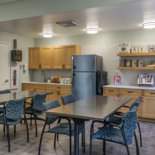 A modern kitchen and dining area with tables, chairs, and a refrigerator.