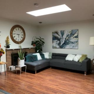 A cozy living room with a modern gray sectional sofa, wooden floors, and a bright skylight.