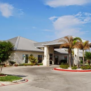 A welcoming residential building under a bright blue sky, surrounded by palm trees.