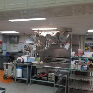 A well-organized commercial kitchen with stainless steel appliances and cooking utensils.