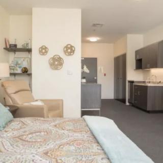 A modern studio apartment featuring a cozy bedroom area and a compact kitchenette.