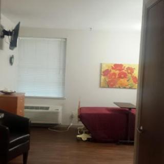 A cozy room featuring a bed, a chair, and artwork on the wall.