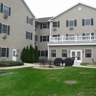A multi-story residential building with a well-maintained lawn and patio area.