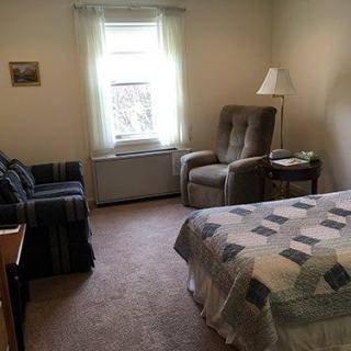 Cozy bedroom with a bed, armchair, and natural light from the window.