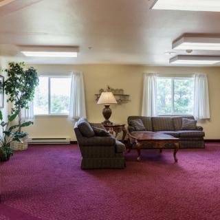 A cozy living room with sofas, a coffee table, and a lamp near large windows.
