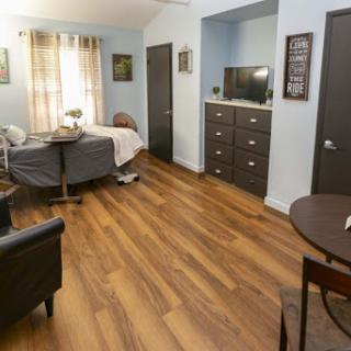 A cozy room featuring a neatly made bed, a small dining table, and modern furnishings.