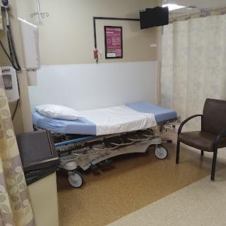 A hospital room featuring a medical bed and a chair, ready for patient care.