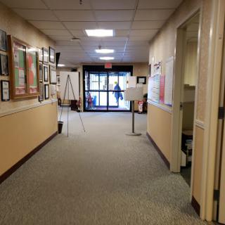 A view of a well-lit hallway leading to an entrance, decorated with posters and surrounded by walls.