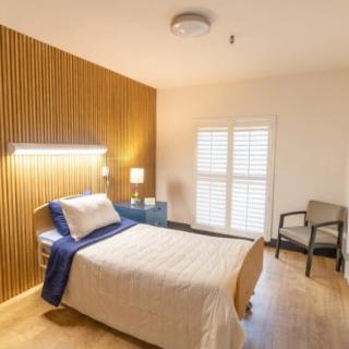 A minimalist bedroom with a single bed and wooden panel accents.