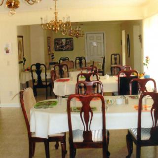 A spacious dining area featuring multiple tables and chairs, lit by a chandelier.