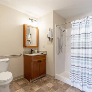 A clean and modern bathroom featuring a toilet, sink with mirror, and a shower with a striped curtain.