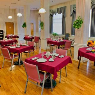 A cozy dining room with tables set for service, featuring red tablecloths and elegant decor.