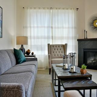 A cozy and well-decorated living room with a sofa, armchair, coffee table, and a fireplace.